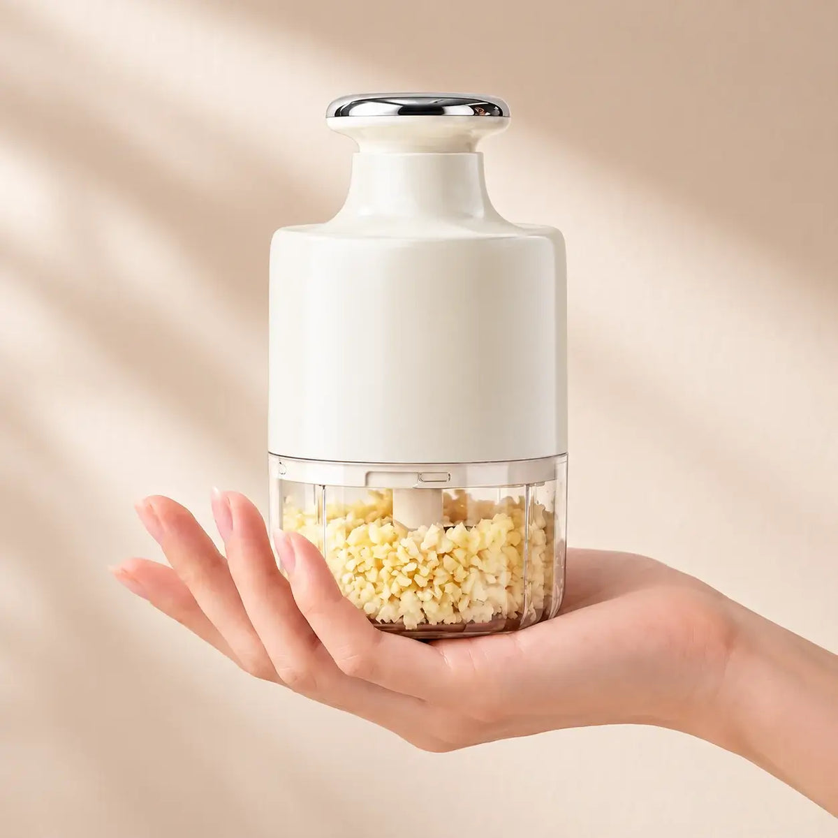 Compact white garlic chopper held in one hand with handle lowered