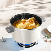 Open Pearl White enamel pot holding chicken soup on a gas stovetop