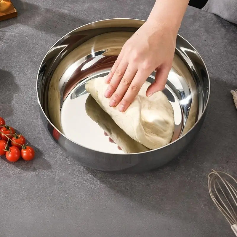 Hands kneading dough in a deep polished stainless steel bowl