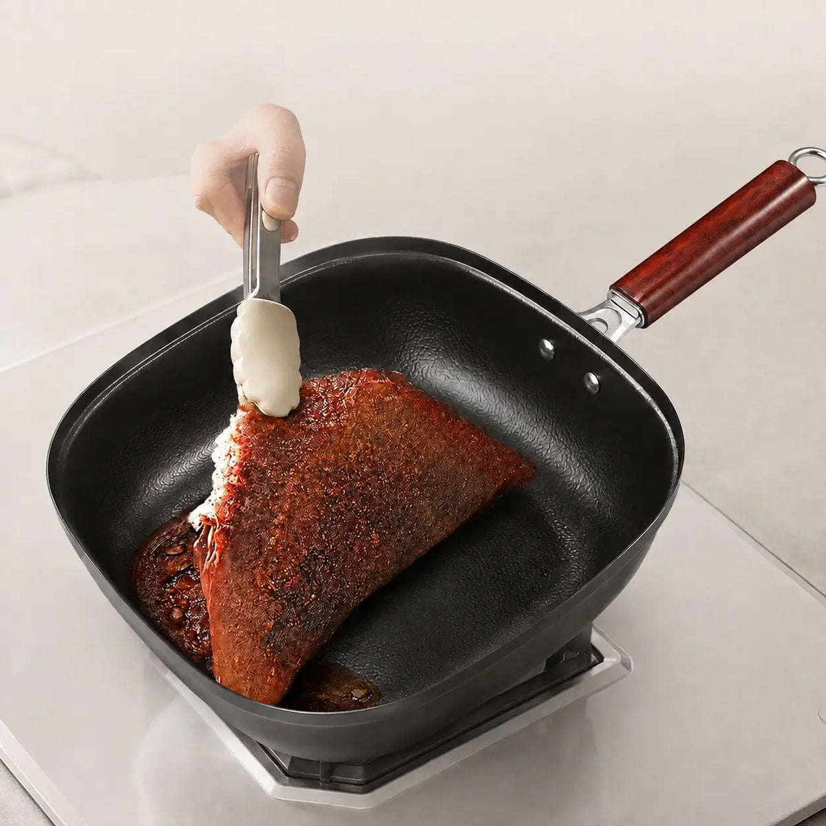 Seared steak being basted in the hammered pan