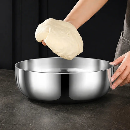 Fresh dough held above a broad stainless steel mixing bowl