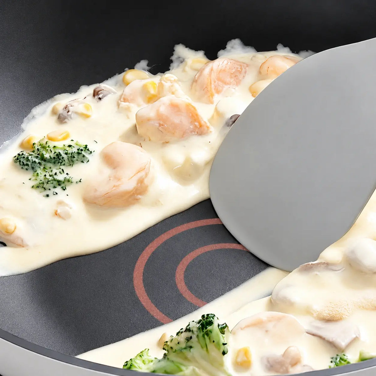 Soft spatula lifting creamy food from the nonstick pan