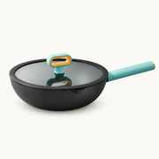 Black titanium nonstick stir-fry pan with blue-green handle and glass lid, shown in full